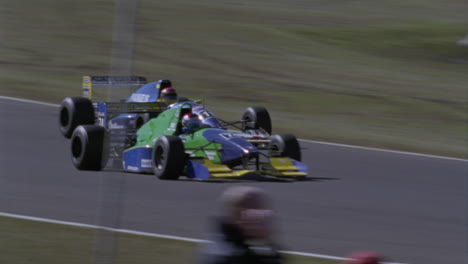 racing cars round a turn in a racetrack people move around