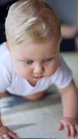 father and son play on the floor at home. cute child crawls by the carpet approaching camera. vertical video.