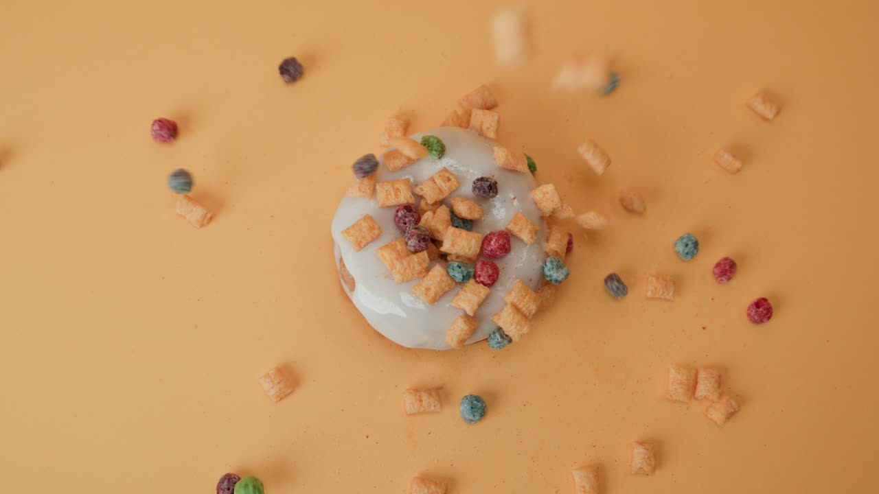 Decorare una ciambella fresca bianca glassata con dolcetti colorati, vista dall'alto