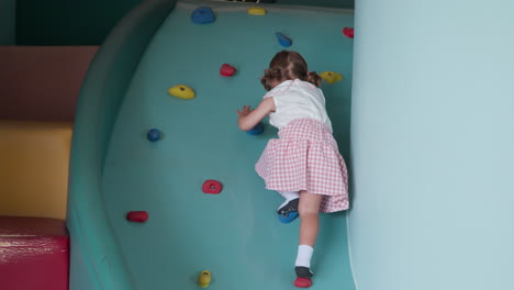 Brave-child-little-girl-is-climbing-up-artificial-wall-at-Indoor-playground