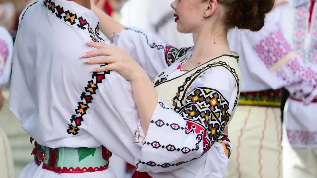 Participants showcase colorful folk costumes and intricate dance moves during a lively cultural festival. The joyful atmosphere highlights community spirit and tradition. Slow motion