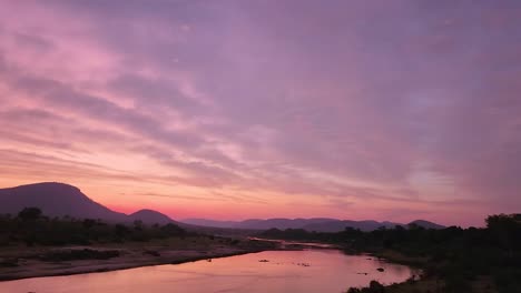 Colorful-sunset-behind-Kruger-Park-mountains-reflecting-on-river