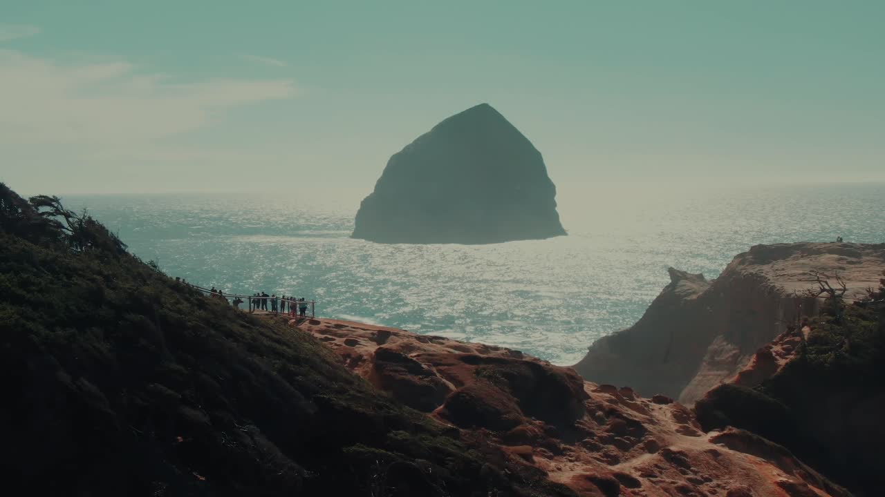 4k Aerial Oregon coast people observing big rock in ocean