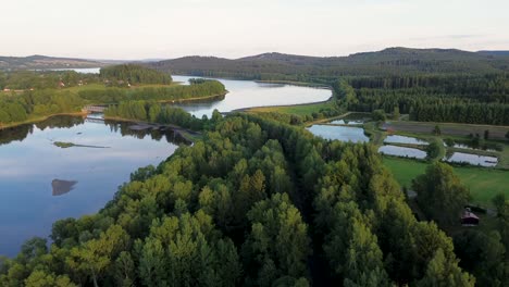 Ein-Blick-Von-Oben-Auf-Einen-Breiten-Blauen-Fluss,-Der-Sich-Zwischen-Wäldern-Und-Wiesen-Schlängelt