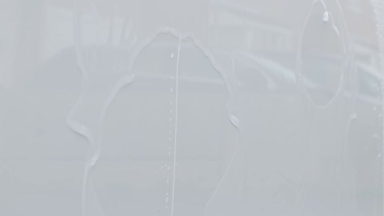 Primo piano estremo di sottili strati d'acqua che scorrono su una superficie verticale dipinta di bianco