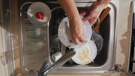 a man washes the dirty dishes in his kitchen the top view