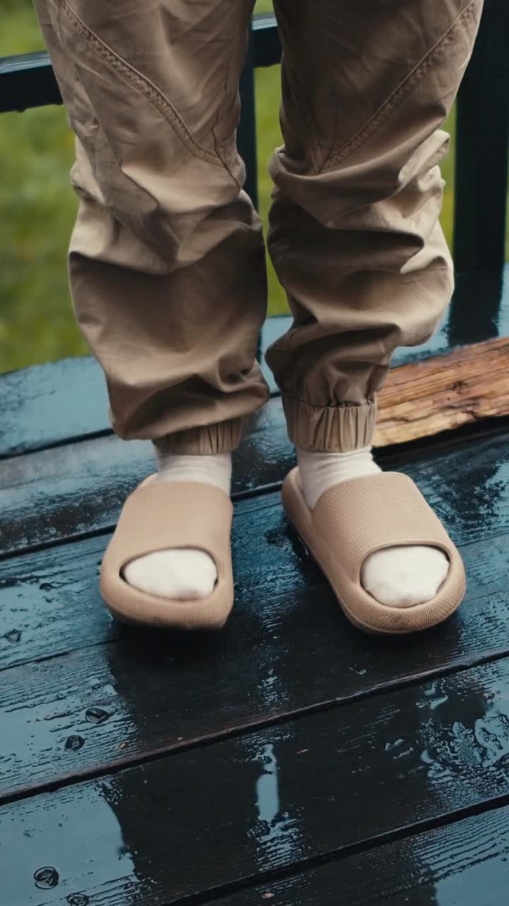 Person wearing beige sandals on wet wooden deck