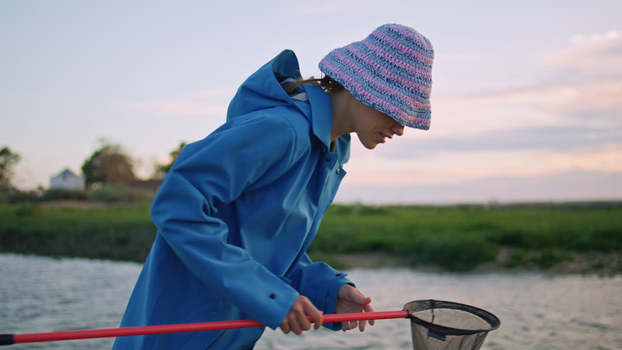 Summer girl catching fish with butterfly net closeup. Smiling woman rest river