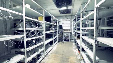 server room for crypto currency mining. row of bitcoin miners set up on the wired shelfs. mining cryptocurrency. bitcoin farm. machines for mining cryptocurrency, bitcoin. electronic device at day