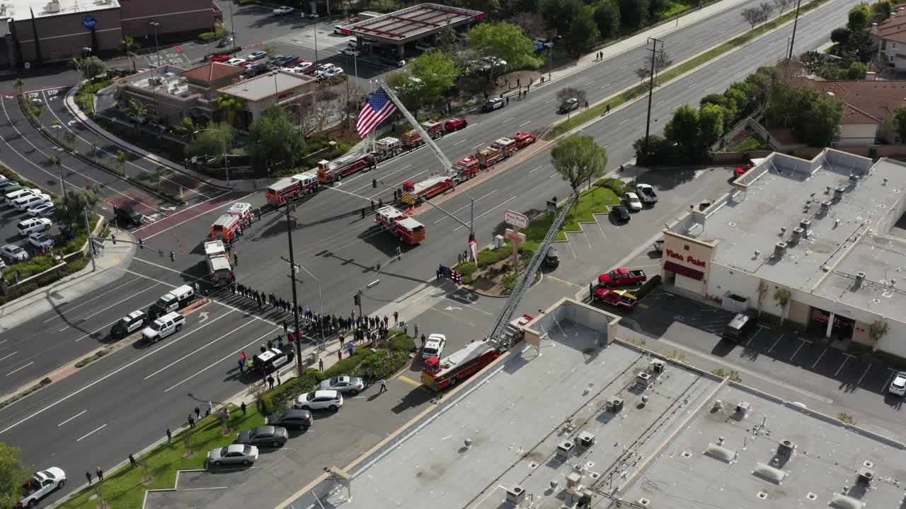 un grupo de tiroteos, policías, camiones de bomberos, camiones de policía esperan una procesión fúnebre para honrar a un oficial caído