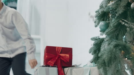 happy boy holding gift and running to christmas tree