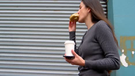 woman eating donuts while walking on street 4k