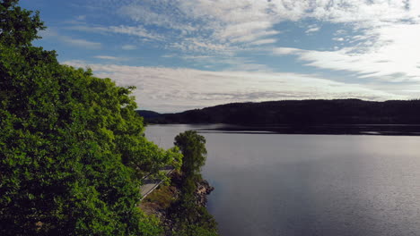 Aerial-of-smooth-water-surface-surrounded-by-green-forest,-pedestal-shot