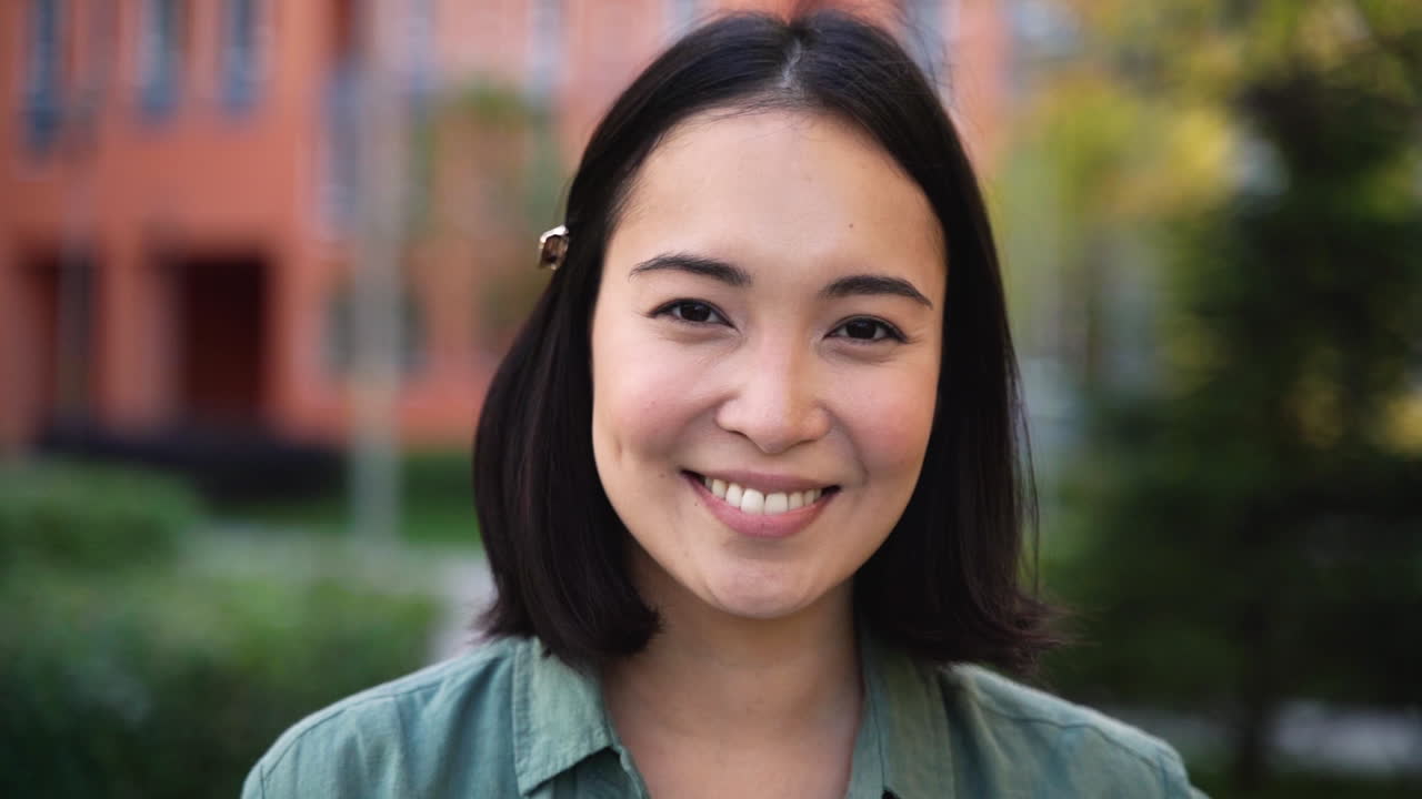 카메라를 보고 웃는 아름다운 일본 소녀의 야외 초상화