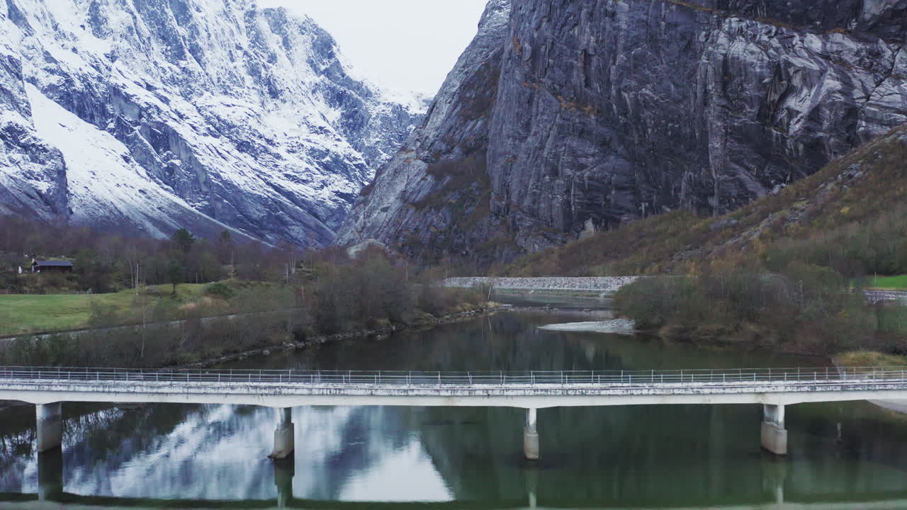 puente sobre el río rauma con el macizo montañoso nevado trollveggen en andalsnes, noruega