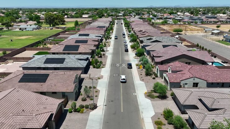 Nedadgående optagelse af en bil, der kører i et moderne kvarter i det sydvestlige USA med mange huse og solpaneler på stuktagene.