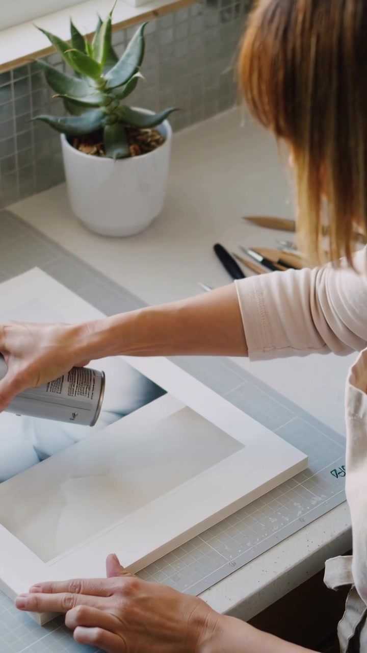 Video verticale: Lattina che viene premuta, artista che spruzza una cornice vicino a una finestra con un grembiule mentre sigilla un'opera d'arte, spazio per il testo