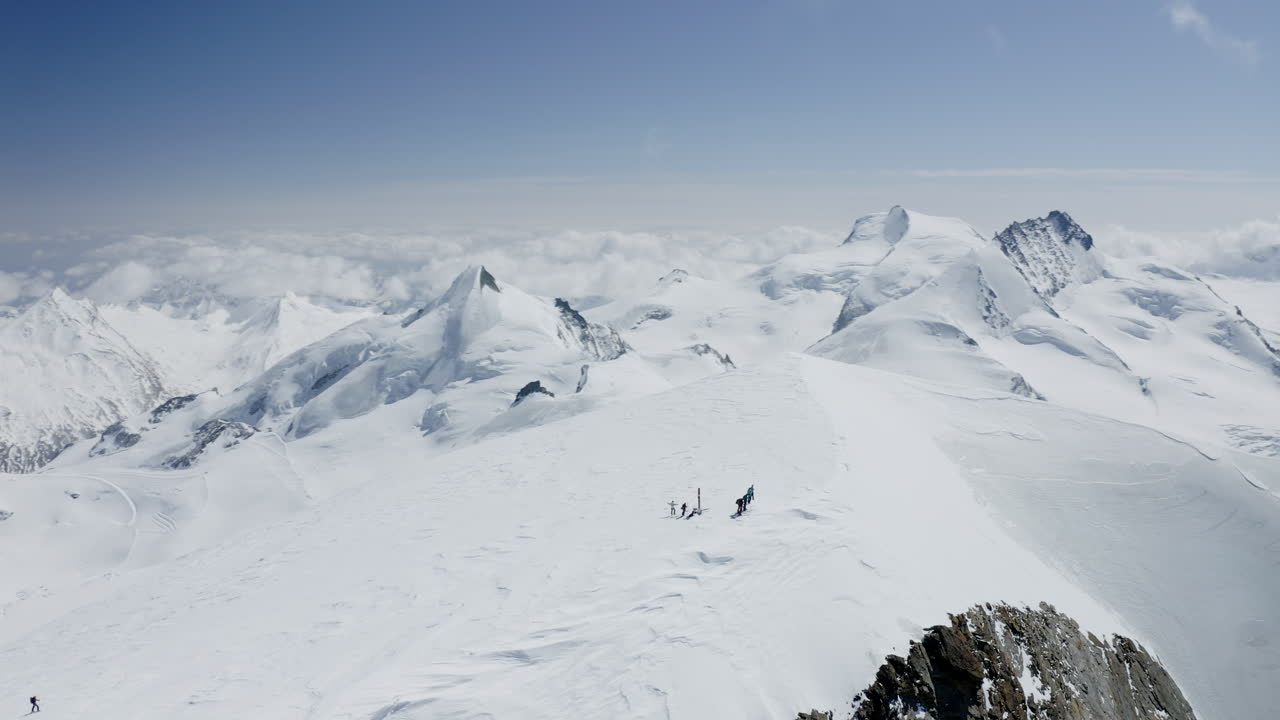 Two freeriders ski tour up the majestic Alphubel with their guide, then descend through glacial terrain surrounded by crevasses and seracs in the high alpine landscape of Saas-Fee
