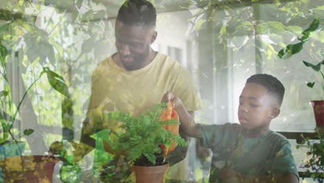 animation of leaves over happy african american father and son watering plant at home