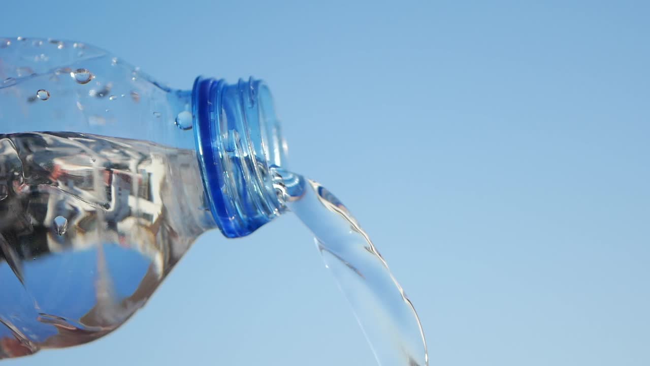 Water Pouring from a Plastic Bottle Against a Blue Sky