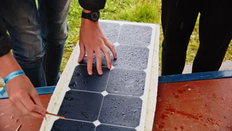 people putting photovoltaic solar panel on top of a wet radio controlled boat