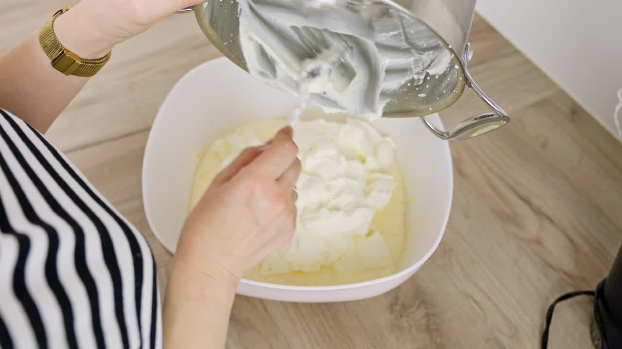Cream is added to a pot containing sugar and egg mix, an essential step in making tiramisu dessert.