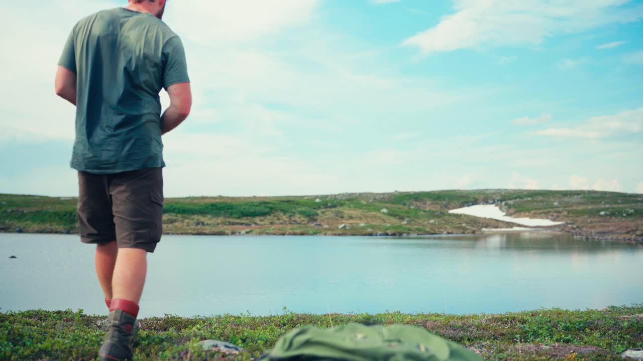 노르웨이 트론델라그의 인드레 포센에서 스쿠르벤에서 메피엘스바트넷으로 가는 길을 산책하는 동안 남성과 그의 개가 호수변에서 휴식을 취하고 있습니다.