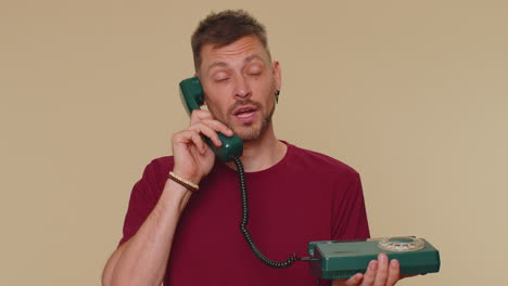 Handsome-man-in-red-t-shirt-talking-on-wired-vintage-telephone-of-80s-says-hey-you-call-me-back