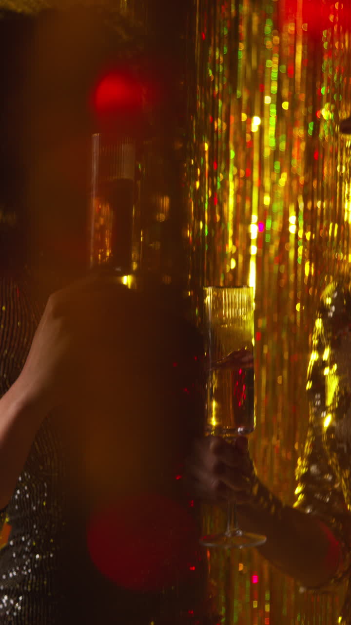 video vertical de dos mujeres en un club nocturno o bar bailando bebiendo alcohol con luces brillantes en el fondo
