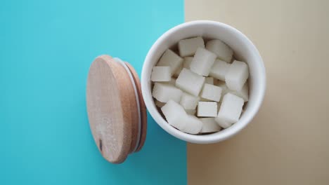 cubos de azúcar en un recipiente blanco con tapa de madera