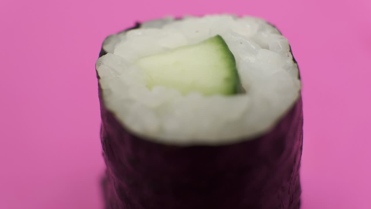 un rollo de sushi girando sobre un fondo rosado