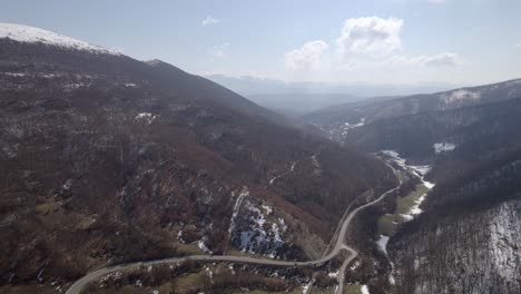 vista aérea de las montañas nevadas de rumania, una carretera con automóviles y un clima soleado de invierno