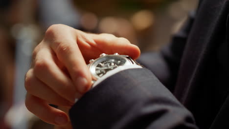 unrecognizable man looking at wrist watch in park. guy hiding watch under sleeve