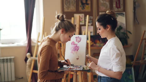 two women painting flowers in an art studio