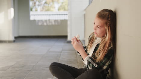 girl sitting in school hallway, eating sandwich, looking thoughtful and relaxed, copy space