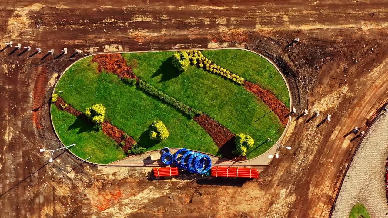 Neue Grünfläche mit Pflanzen und Materialien auf einem unbebauten Gelände, die eine Landtransformation zeigt