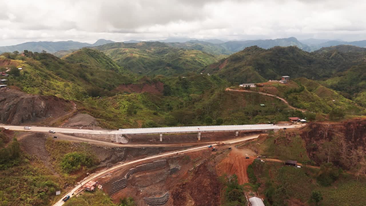 Drone shot of a bridge under construction in green mountain landscape. Ideal for infrastructure, engineering, and rural development visuals