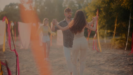 una pareja joven bailando bachata en la playa.