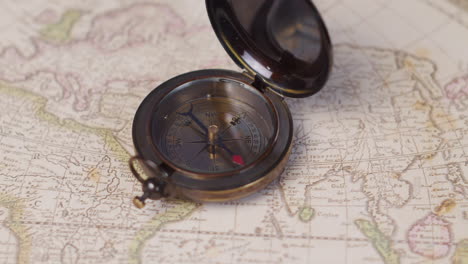 close up od an antique brass compass on a vintage world map