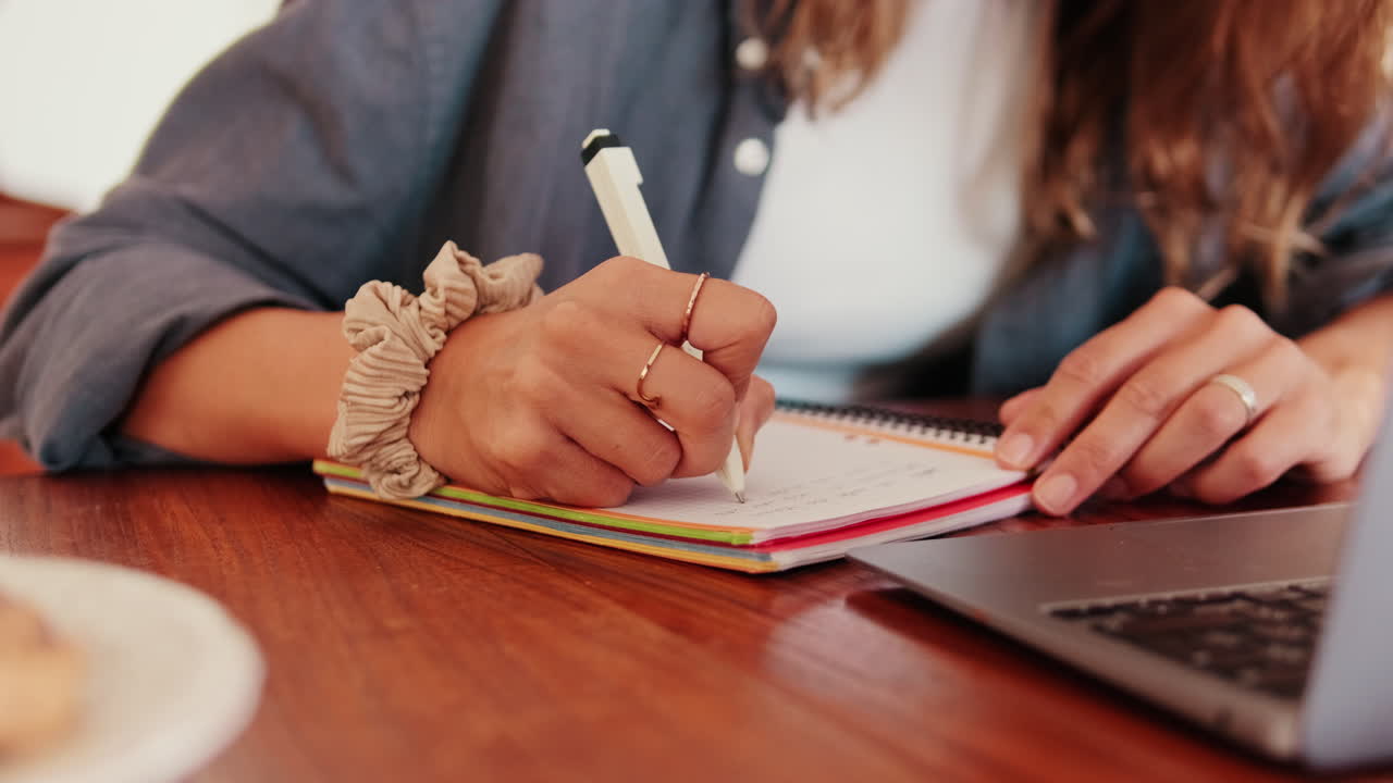 Close Up of Woman's Hand Writing in Notebook at Desk