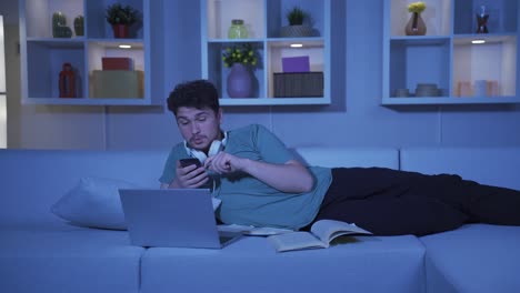 man using social media on phone laughing at night at home.