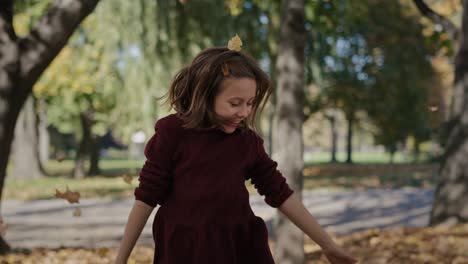 portrait of smiling little girl which throwing up autumn leaves.