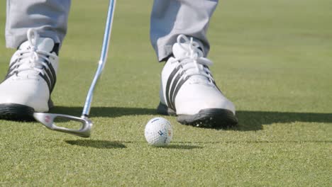 Nahaufnahme-Bewegungsspur-Kurzes-Eisen,-Golfer-Putzen-Golfball,-Sonniger-Grüner-Kurs