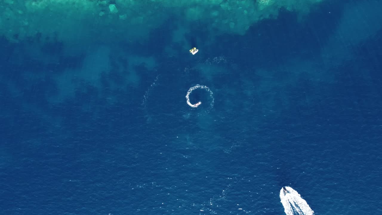 순수한 티르코이즈 마법의 바다에서 아름다운 모양을 만들고 원을 돌아다니는 빠른 스피드 보트의 공중 전망.