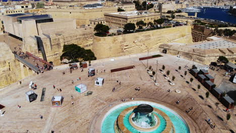 Flying-over-the-Triton-Fountain-at-the-entrance-of-Valletta,-Malta