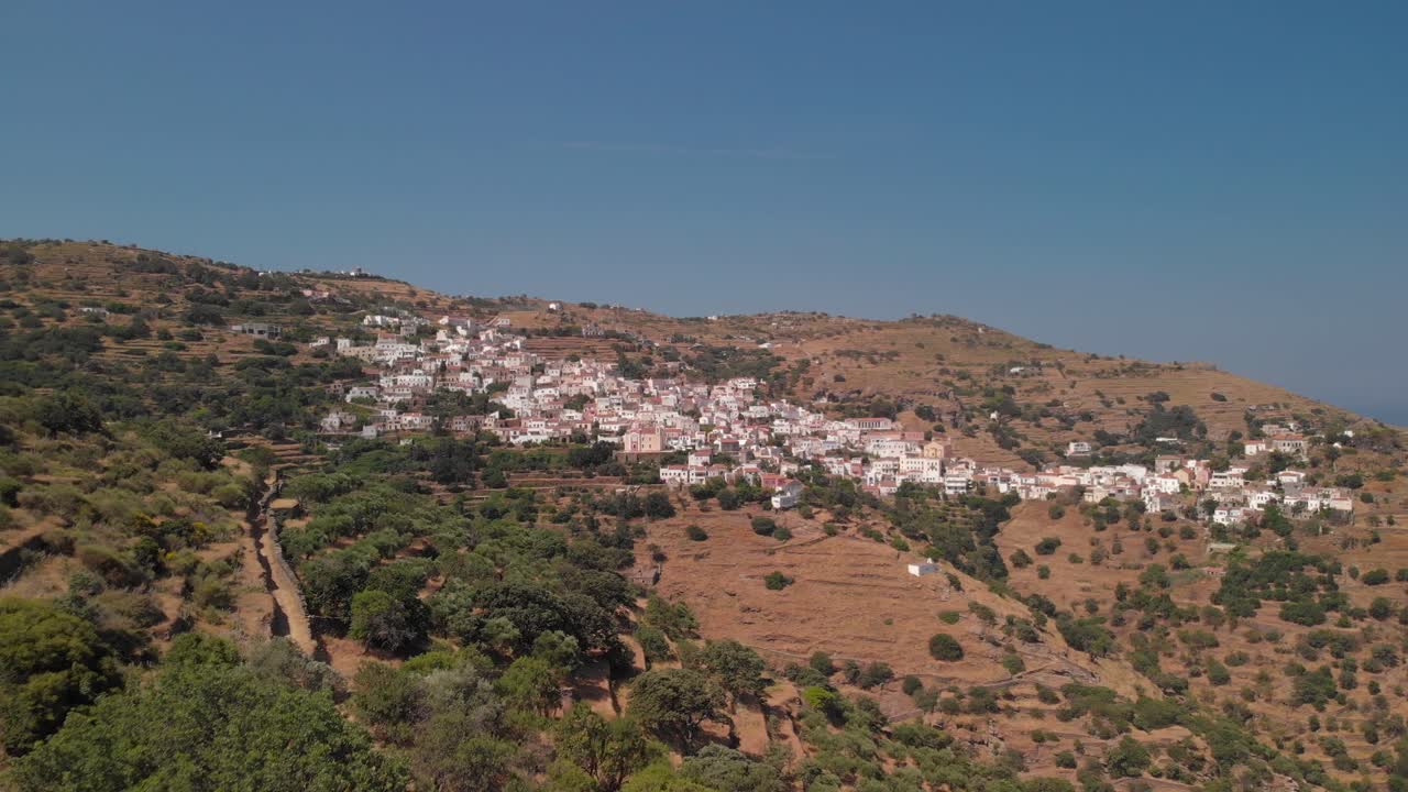 avance aéreo hacia la aldea de ioulida en la isla de kea elevándose detrás de los árboles