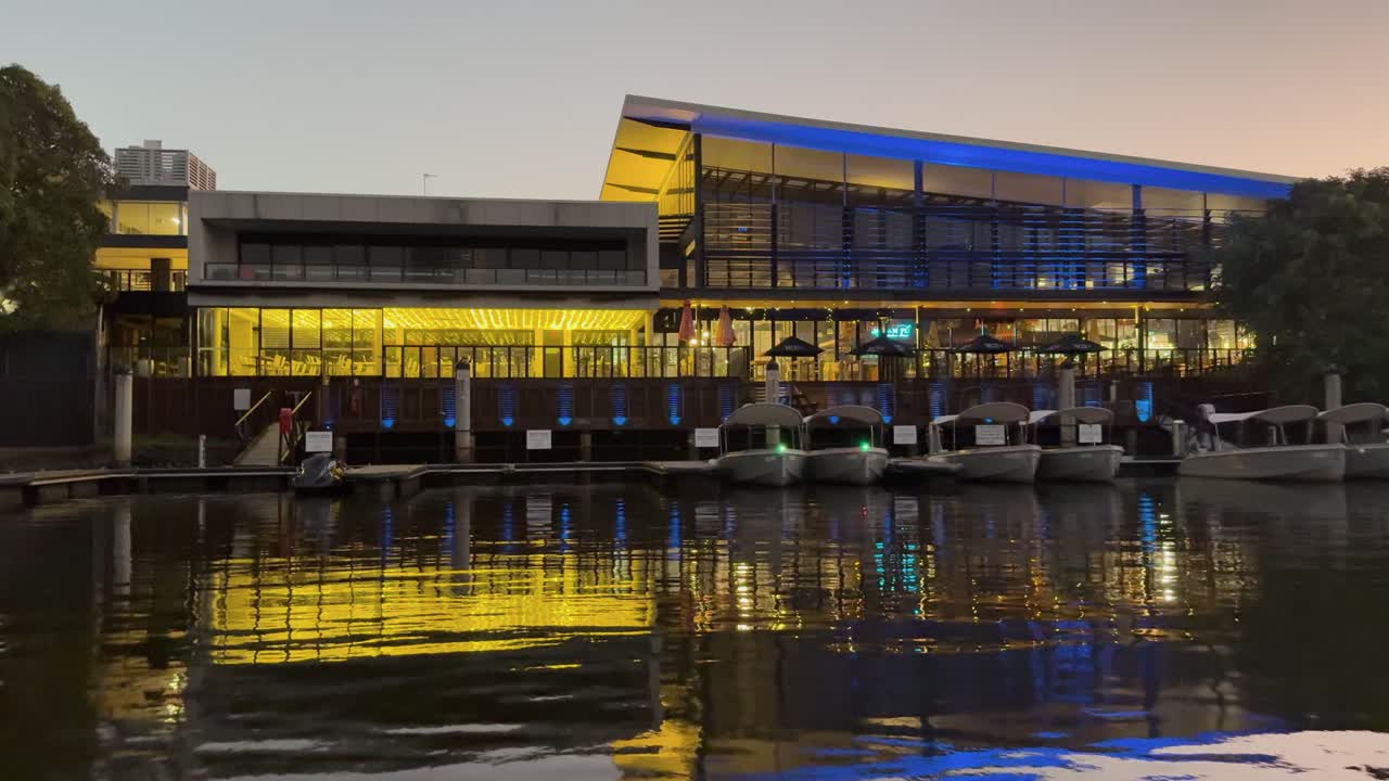 A vibrant riverfront restaurant with colorful lighting reflecting on water at night in Gold Coast, Australia