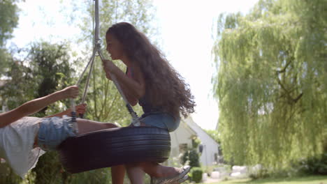 two girls playing on tire swing in garden