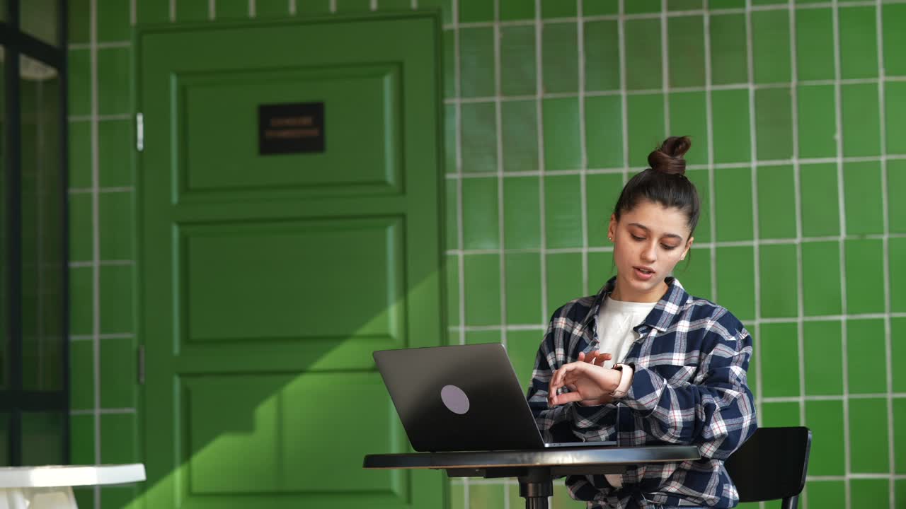 mujer joven trabajando en una computadora portátil en un café al aire libre