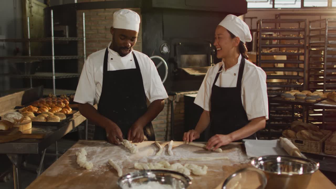 Animation of happy diverse female and male bakers preparing rolls at bakery